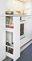A pull-out shelf in a white kitchen unit