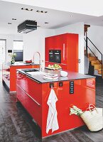 Two red islands and a red cupboard with fitted appliances in a kitchen