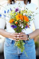 Hands holding a bouquet of wild summer flowers