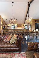Vintage leather couch, long dining table and kitchen in converted barn