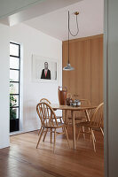 Spoke-back chairs around pale wooden kitchen table next to fitted cupboards