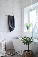 Free-standing bathtub in bathroom with white wall tiles and window