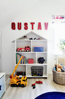Name written in red letters above house-shaped shelving in child's bedroom