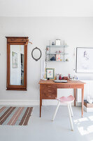 Old mirror on wall and desk in bright room with grey floor