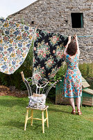 Woman wearing floral dress hanging up laundry to dry in garden