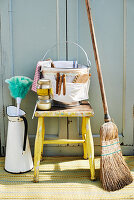 Bucket of cleaning utensils on stool with besom broom and feather duster