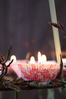 Suspended Advent wreath made from branches decorated with candles in paper cake cases (close-up)