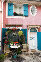 Romantic seating area outside pink house with blue shutters