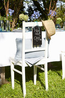 White garden chair with place card and straw hat at an outdoor table setting