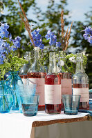 Summery lemonade bottles and blue glasses on wooden table in the garden