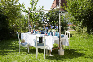 Summery garden table with blue glass vases and white chairs