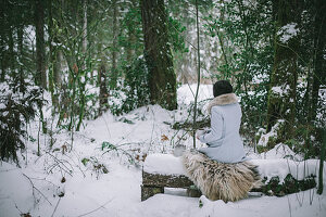 Frau trinkt Tee im verschneiten Wald