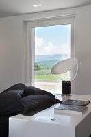 Designer lamp on white surface next to bed with black bed linen in bedroom