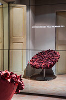 Red designer armchair reflected in mirrored cabinet with illuminated lettering