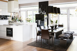 Black, modern dining set in front of white, open-plan kitchen