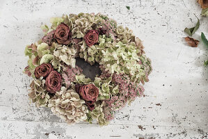 Handmade hydrangea and rose wreath on white shabby-chic table