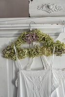 Antique nightie hung from coat hanger wrapped in hydrangea flowers
