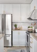 White kitchen with light wood accents, stainless appliances and white subway tiles