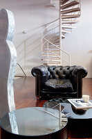 Leather armchair and coffee table in front of spiral staircase in living room