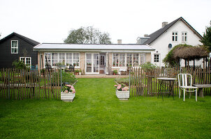 Entrance flanked by planted troughs in paling fence around garden and house