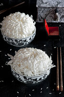 Two white chrysanthemums (Chrysanthemum) in black and white porcelain bowls