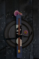 Black plate with chopsticks and flowers on a dark wooden table