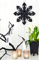 Black paper star on white wall, hyacinth and lanterns