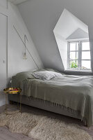 Bed, bedside table, and animal fur rug in the attic bedroom