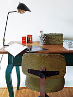 An old swivel chair in front of a wooden table used as a desk