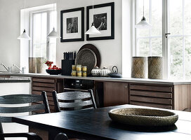 Schwarz lackierter Holztisch mit Stühlen, im Hintergrund Küchenzeile vor Fenster