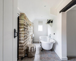 Free-standing bathtub and exposed stone wall in bathroom