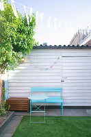 Pale blue bench and folding table providing a splash of colour in a courtyard garden