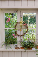 Wreath and plants in window with view of summer garden