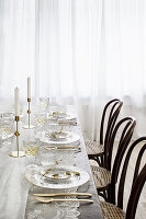 Bistrostühle am gedeckten Tisch mit Tischdecke aus Spitze