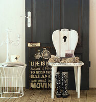 Old, shabby-chic farmhouse chair against black panelled door