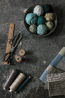 Sewing tools, spools of thread and fabric samples on concrete floor