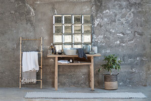 Rustikaler Holztisch mit Waschschüssel vor Glasbausteinfenster und Handtuchhalter