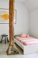 Single bed next to wooden pillar in white room