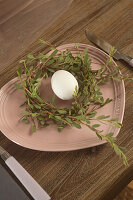 Egg in twig wreath on pink, heart-shaped plate