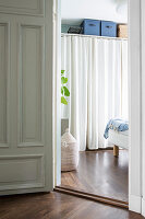 View through open door in bedroom with wardrobe behind curtain