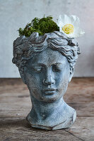 Blumentopf in Kopf-Form mit Moos und einer Christrose