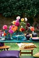 Dahlias in blue glass vase on set table outdoors