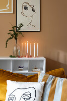 Handmade candle holders below one-line drawing on brown wall