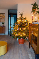 Illuminated Christmas tree in living room decorated in mid-century modern style