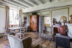 Antique armchairs, wooden cupboards and stone table with chairs in interior with tiled floor