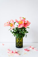 Fading peonies in green structured glass vase