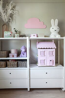 Pink dolls' house, baskets and Miffy nightlight on white shelves