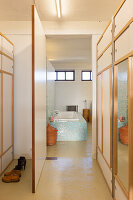 Einbauten auf dem Flur, Blick ins Bad auf eingebaute Badewanne mit Mosaikfliesen