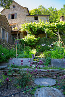 Summer garden and a natural stone house on slopping grounds