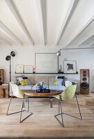 Couchtisch mit Holzplatte und filigrane Stühle vor Sofa in Loft-Wohnung